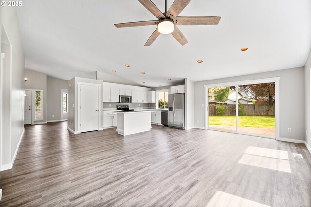 unfurnished living room featuring light wood-type flooring, baseboards, ceiling fan, and vaulted ceiling