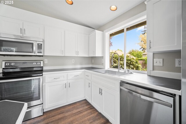 kitchen featuring dark wood-type flooring, recessed lighting, white cabinets, a sink, and stainless steel appliances