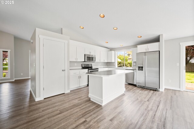 kitchen with a kitchen island, white cabinets, appliances with stainless steel finishes, and light wood-style flooring