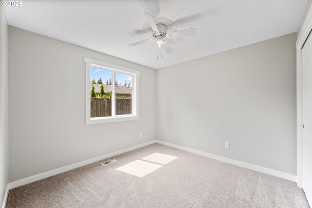 carpeted spare room featuring baseboards, a ceiling fan, and visible vents