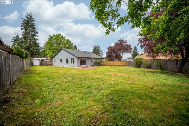 view of yard featuring a fenced backyard, a patio area, a shed, and an outbuilding