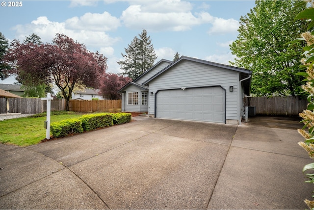 view of front facade with concrete driveway, fence, a front lawn, and a garage