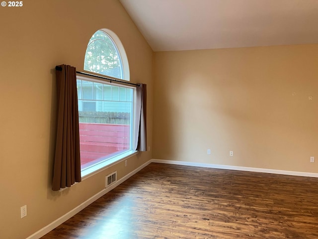 spare room with dark hardwood / wood-style floors and vaulted ceiling