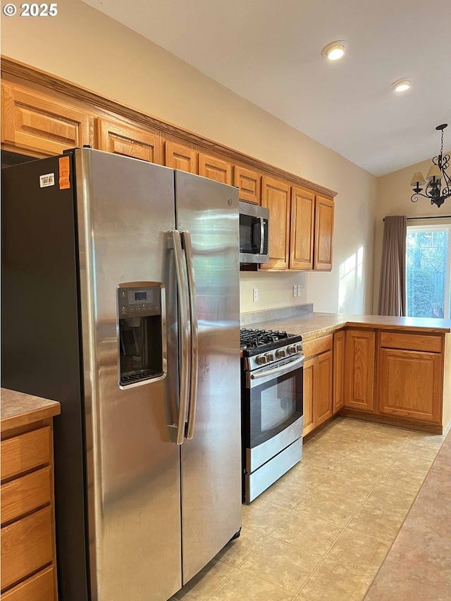 kitchen featuring kitchen peninsula, appliances with stainless steel finishes, vaulted ceiling, a notable chandelier, and hanging light fixtures