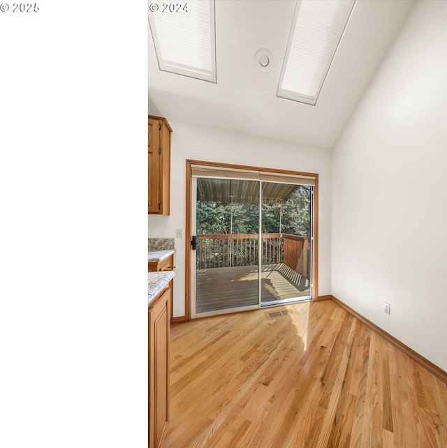 unfurnished dining area featuring vaulted ceiling and light hardwood / wood-style flooring