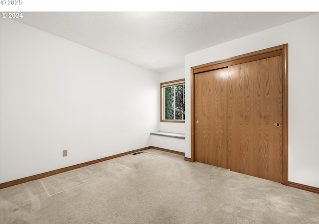 unfurnished bedroom with light colored carpet and a closet