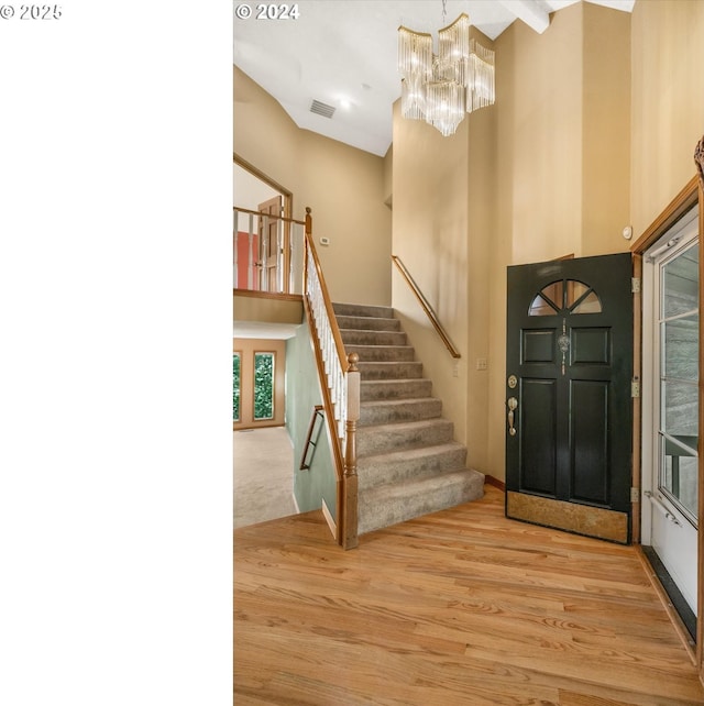 foyer entrance featuring light hardwood / wood-style flooring, a high ceiling, and an inviting chandelier