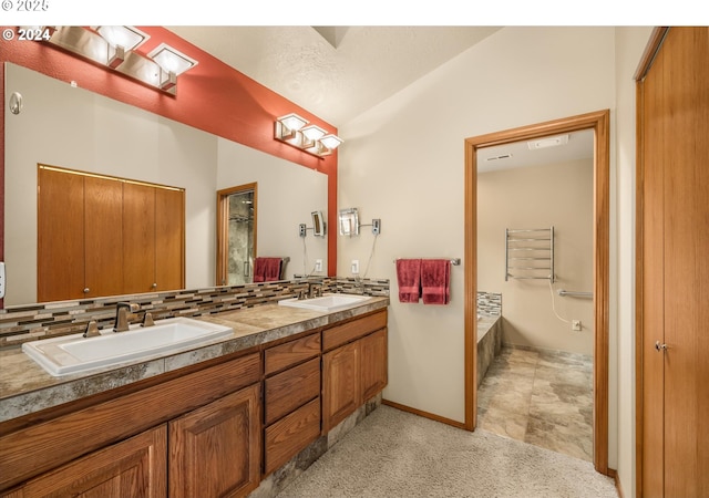 bathroom with a bathing tub, vanity, lofted ceiling, and backsplash