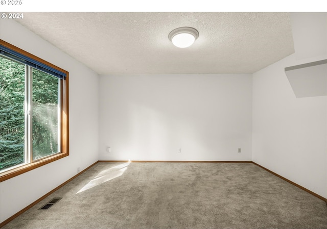 carpeted empty room with a textured ceiling