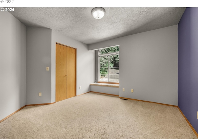 carpeted empty room with a textured ceiling