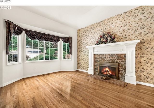 unfurnished living room featuring hardwood / wood-style flooring and a brick fireplace