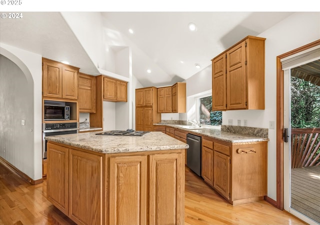 kitchen featuring stainless steel appliances, vaulted ceiling, light hardwood / wood-style floors, a kitchen island, and plenty of natural light