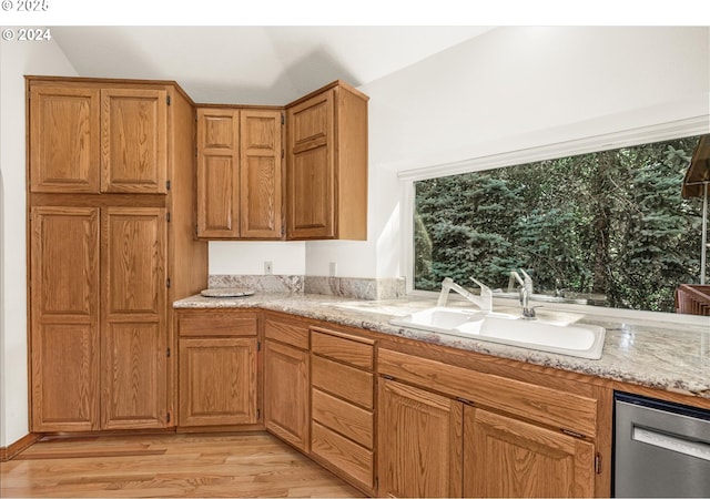 kitchen with light stone countertops, stainless steel dishwasher, lofted ceiling, and sink