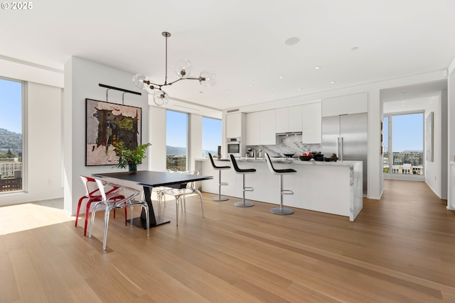 dining space with light wood-type flooring, a notable chandelier, and recessed lighting