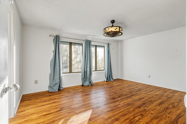 spare room featuring a textured ceiling and light hardwood / wood-style flooring