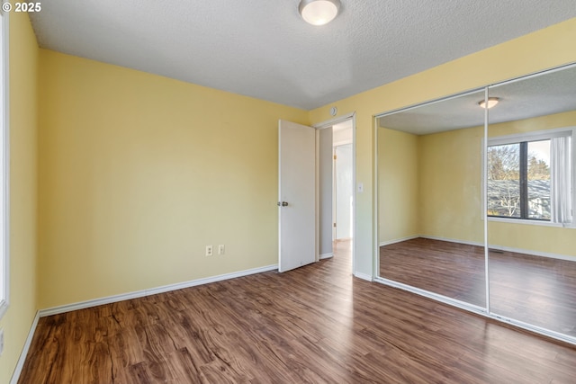 unfurnished bedroom featuring a closet, a textured ceiling, and wood-type flooring