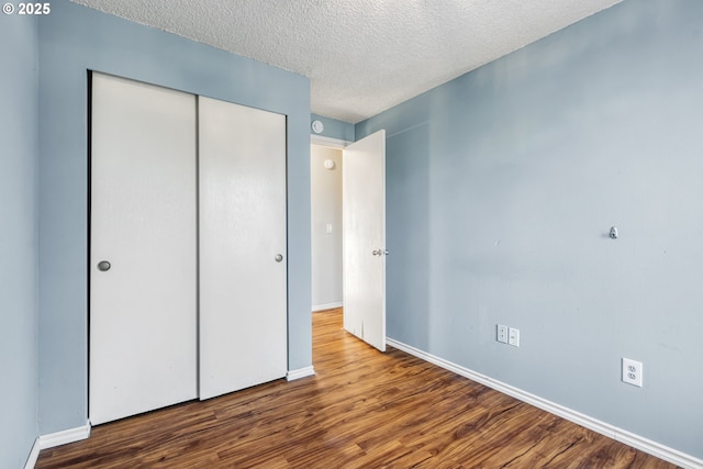 unfurnished bedroom with hardwood / wood-style floors, a textured ceiling, and a closet