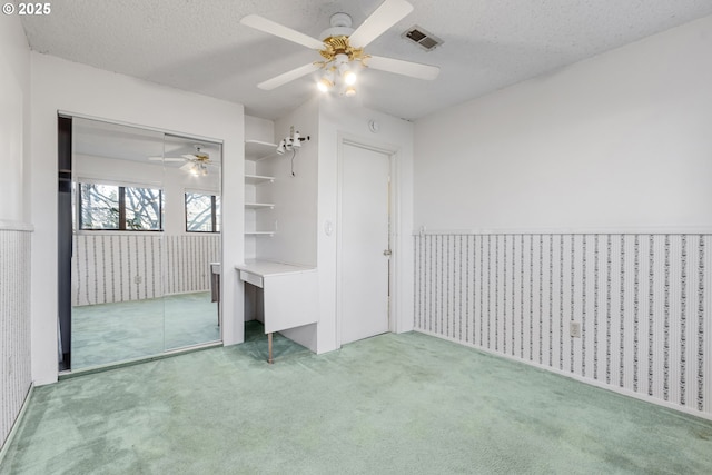 unfurnished bedroom featuring ceiling fan, a textured ceiling, a closet, and carpet flooring