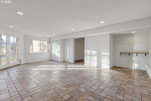 unfurnished living room with french doors, a healthy amount of sunlight, and a textured ceiling