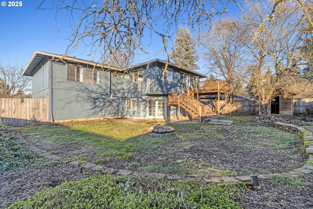 back of property featuring a deck, a fire pit, and a lawn