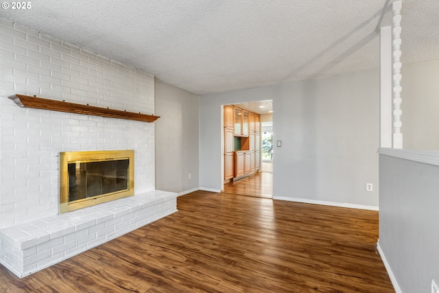 unfurnished living room with a fireplace, a textured ceiling, and wood-type flooring