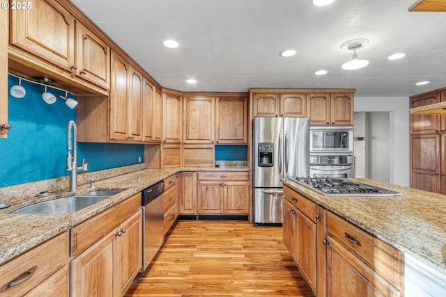 kitchen featuring light stone countertops, sink, stainless steel appliances, and light wood-type flooring