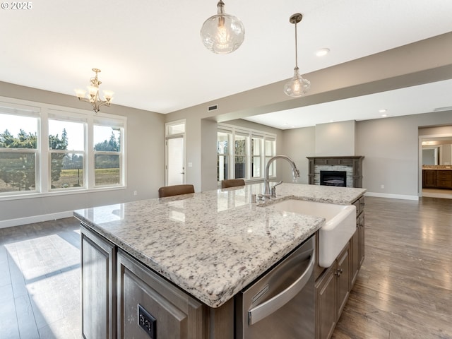 kitchen featuring dishwasher, sink, a center island with sink, and decorative light fixtures