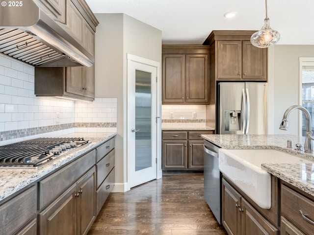 kitchen with extractor fan, appliances with stainless steel finishes, dark hardwood / wood-style floors, pendant lighting, and sink