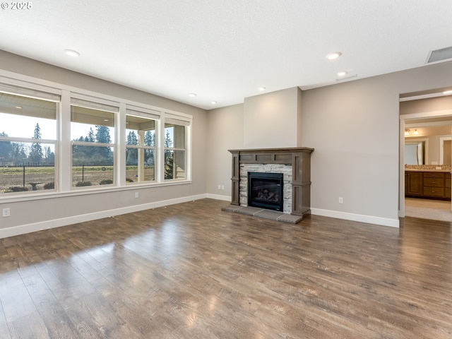 unfurnished living room with dark hardwood / wood-style floors, a stone fireplace, and a textured ceiling