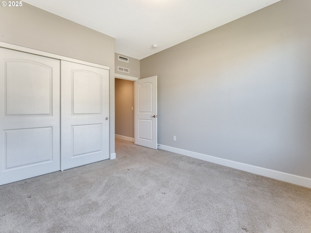 unfurnished bedroom featuring light colored carpet and a closet