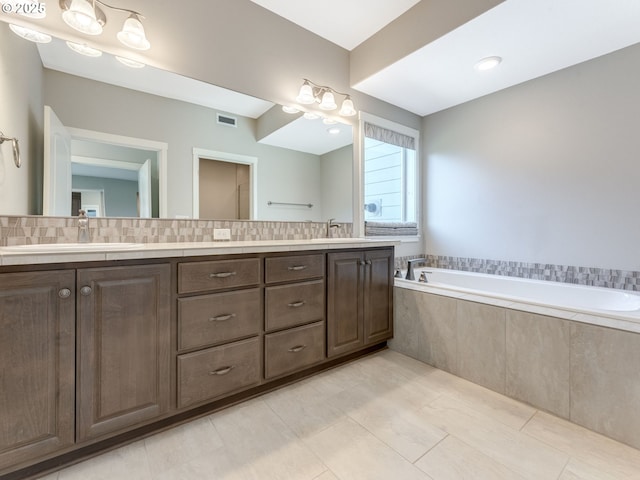 bathroom with tile patterned flooring, vanity, a relaxing tiled tub, and backsplash