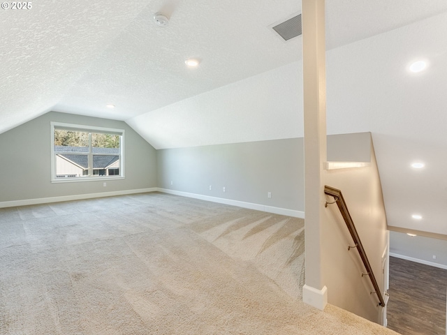 bonus room featuring carpet floors, vaulted ceiling, and a textured ceiling