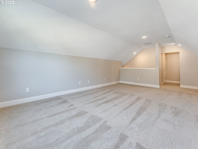 additional living space with lofted ceiling, light carpet, and a textured ceiling