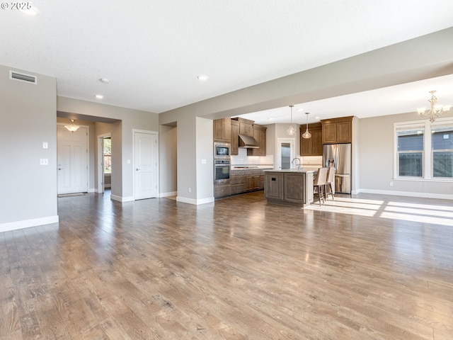 unfurnished living room with an inviting chandelier, hardwood / wood-style floors, and sink