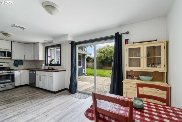 567 NW Cedar Ct, Warrenton, OR 97146 - kitchen with appliances with stainless steel finishes, light wood-type flooring, and glass insert cabinets
