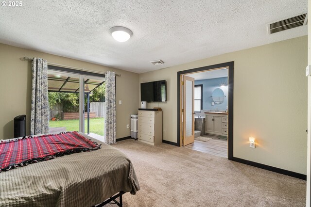 567 NW Cedar Ct, Warrenton, OR 97146 - bedroom featuring light colored carpet, access to exterior, connected bathroom, and a textured ceiling