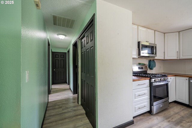 567 NW Cedar Ct, Warrenton, OR 97146 - kitchen featuring stainless steel appliances, light wood finished floors, white cabinetry, and wooden counters