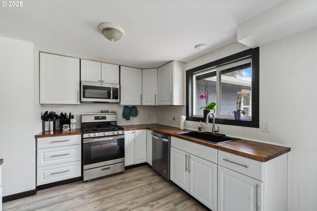 567 NW Cedar Ct, Warrenton, OR 97146 - kitchen featuring wood counters, appliances with stainless steel finishes, white cabinets, and light wood finished floors