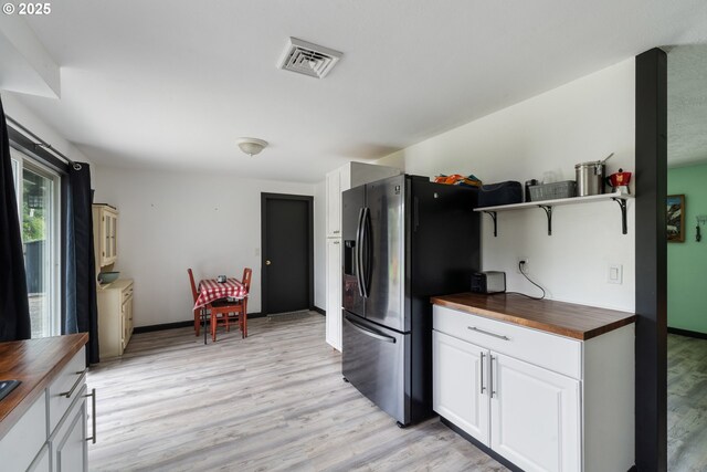 567 NW Cedar Ct, Warrenton, OR 97146 - kitchen featuring wooden counters, light wood-type flooring, stainless steel fridge, open shelves, and white cabinets