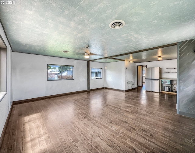 interior space featuring baseboards, visible vents, ceiling fan, and dark wood-style flooring