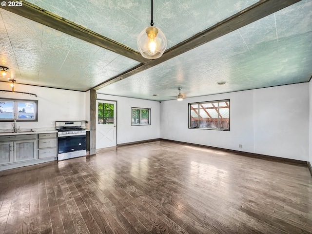 unfurnished living room featuring hardwood / wood-style floors, a ceiling fan, baseboards, and a sink