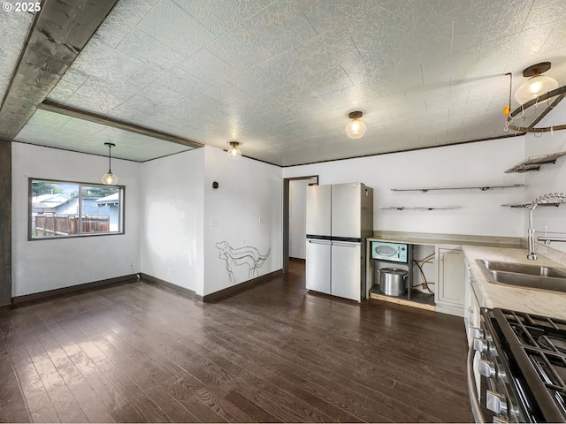 kitchen featuring open shelves, stainless steel appliances, light countertops, dark wood-type flooring, and a sink