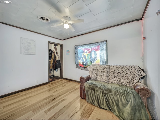 sitting room with light wood finished floors, baseboards, visible vents, a ceiling fan, and crown molding