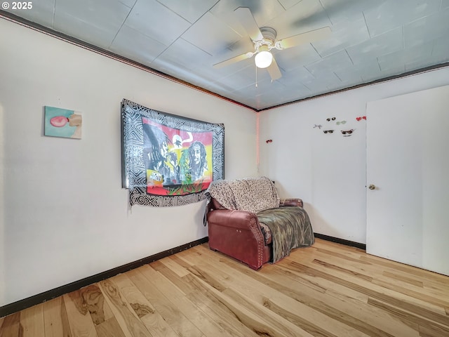 sitting room with a ceiling fan, baseboards, and light wood finished floors