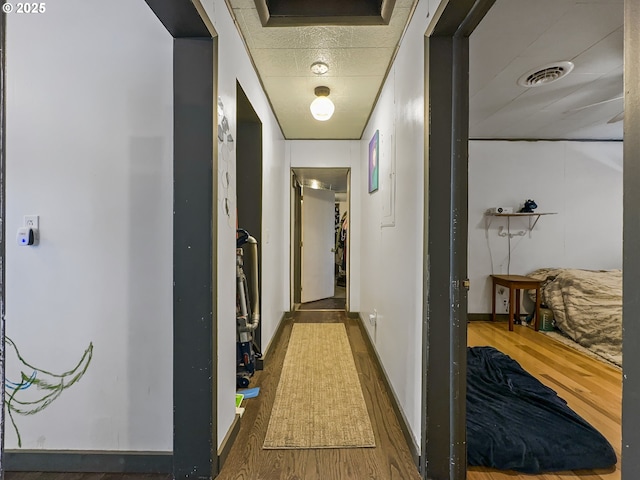 hall featuring dark wood-style floors, visible vents, and baseboards