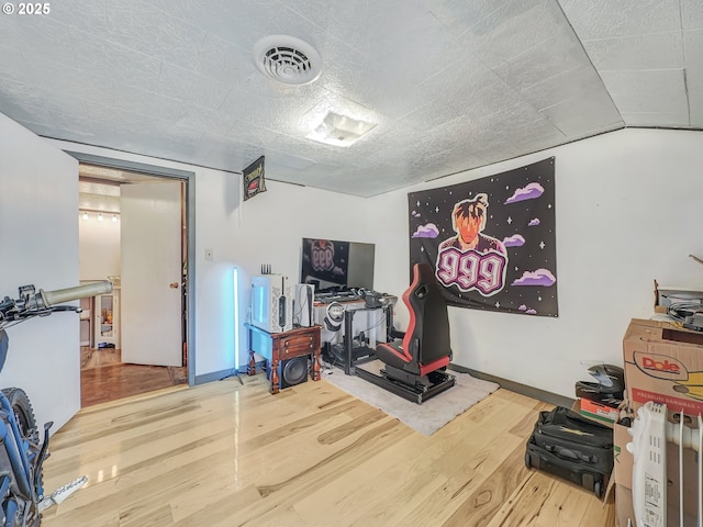 workout room with a textured ceiling, wood finished floors, visible vents, and baseboards