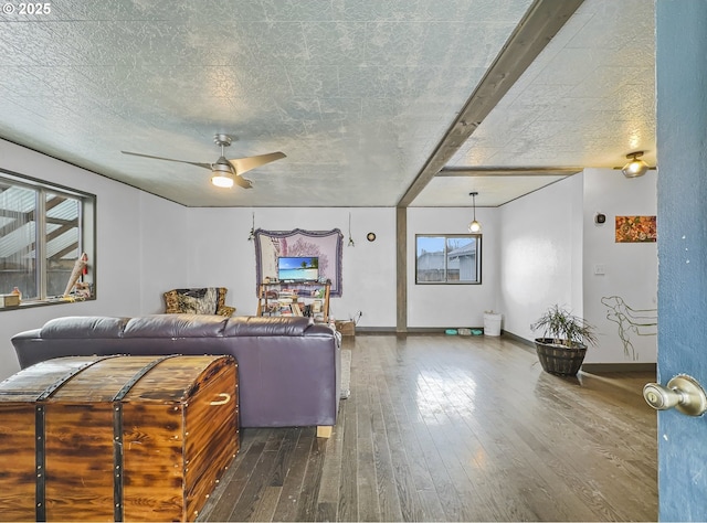 living room featuring dark wood-style floors, ceiling fan, baseboards, and a textured ceiling