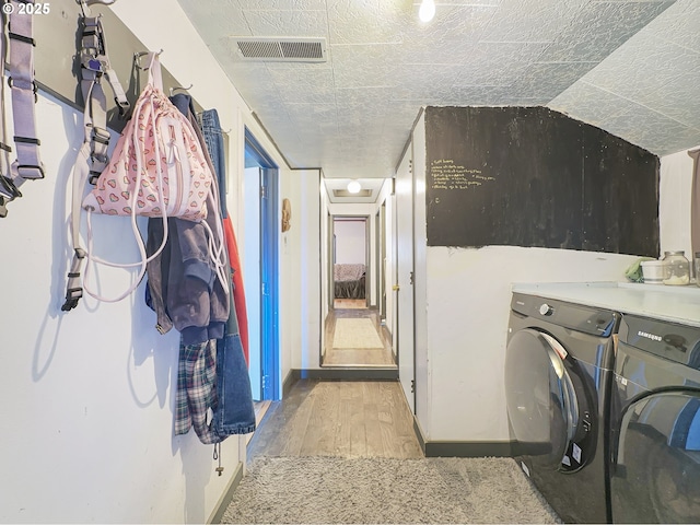 washroom with light wood-type flooring, visible vents, a textured ceiling, and independent washer and dryer