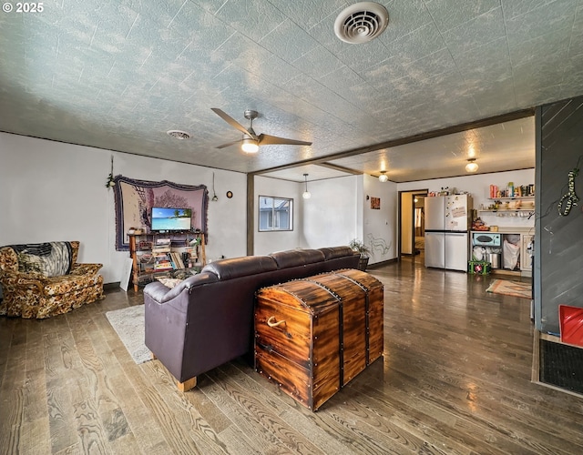 living area featuring a ceiling fan, visible vents, and wood finished floors