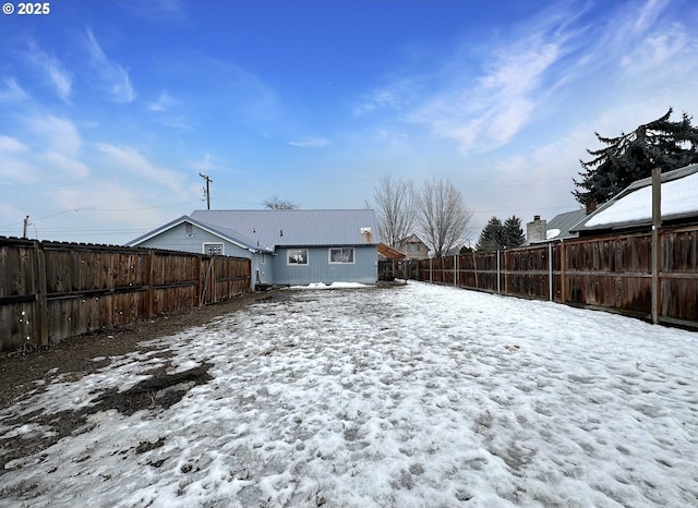 snow covered rear of property featuring a fenced backyard